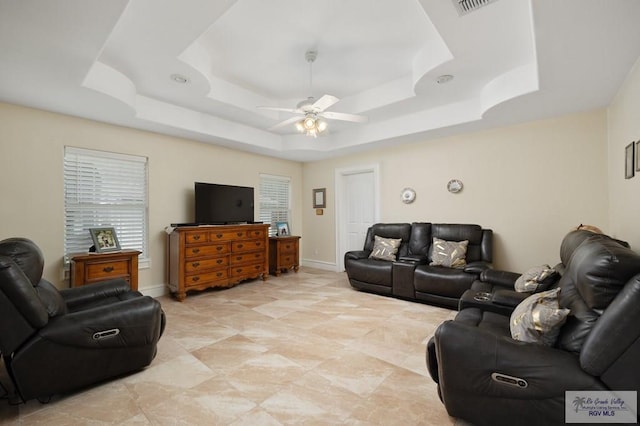 living room featuring a raised ceiling and ceiling fan