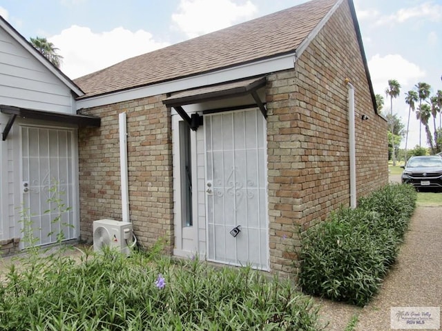 225 Country Club Rd Unit 225, Brownsville, TX 78520 - doorway to property with ac unit, brick siding, and a shingled roof