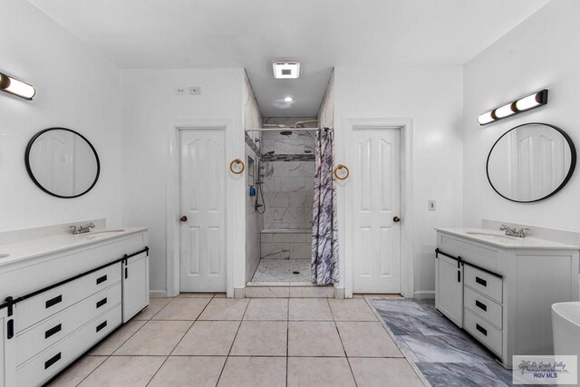 bathroom featuring tile patterned flooring, vanity, and tiled shower