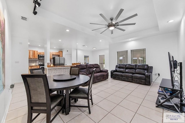 dining room with light tile patterned floors, a raised ceiling, and ceiling fan