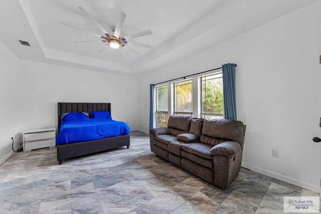 bedroom with ceiling fan and a raised ceiling