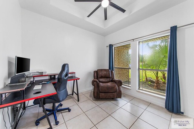 tiled home office with plenty of natural light, ceiling fan, and a tray ceiling