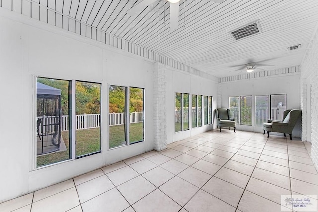 unfurnished sunroom featuring ceiling fan and a healthy amount of sunlight