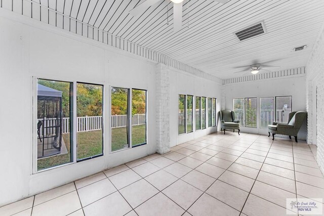 unfurnished sunroom featuring ceiling fan and a healthy amount of sunlight