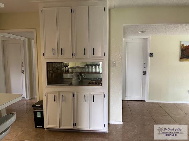 interior space featuring white cabinets, a textured ceiling, and dark tile patterned flooring