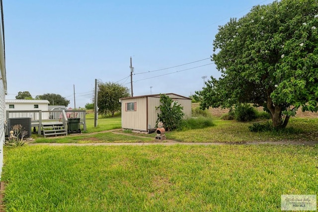 view of yard with central air condition unit, a wooden deck, and a storage shed