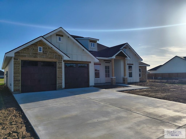 9728 Heights S Unit 9, Harlingen, TX 78552 - view of front of property with board and batten siding, driveway, a garage, and stone siding