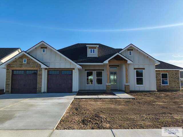 9728 Heights S Unit 9, Harlingen, TX 78552 - view of front facade featuring board and batten siding, an attached garage, stone siding, concrete driveway, and roof with shingles