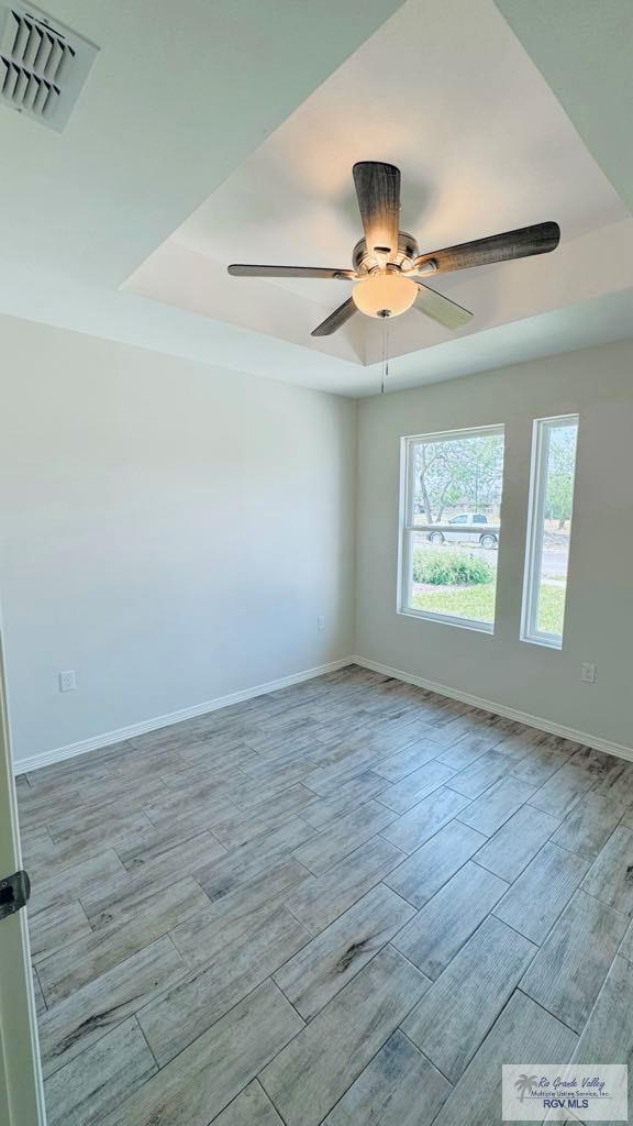 empty room featuring ceiling fan and a tray ceiling