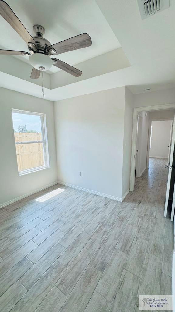 unfurnished room featuring ceiling fan and a tray ceiling