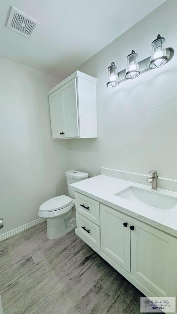 bathroom with vanity, toilet, and hardwood / wood-style floors