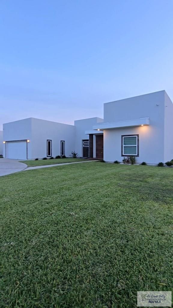 contemporary home featuring a garage, stucco siding, and a front lawn