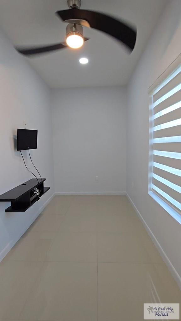 interior space featuring light tile patterned floors, baseboards, and ceiling fan