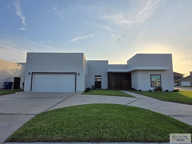 contemporary house with curved driveway, a front lawn, an attached garage, and stucco siding