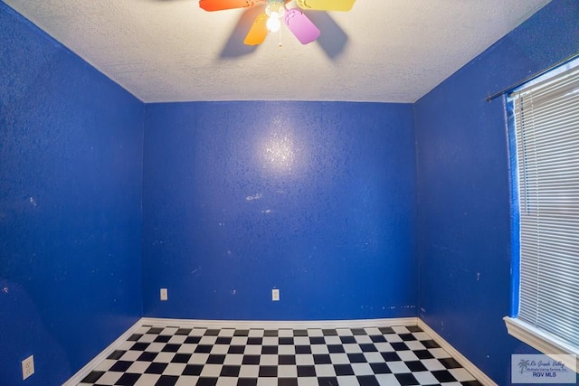 spare room featuring tile patterned floors, baseboards, a textured ceiling, and a ceiling fan