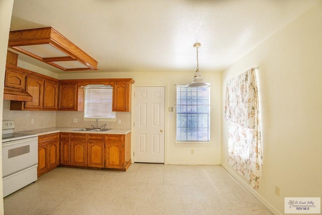 kitchen featuring white electric stove, under cabinet range hood, brown cabinetry, and a sink