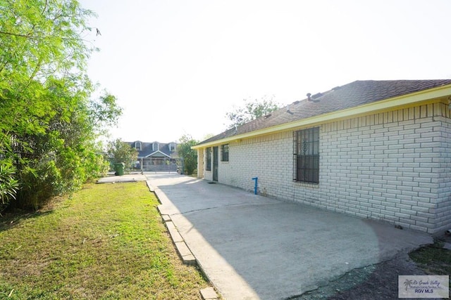 view of side of property with brick siding and a lawn