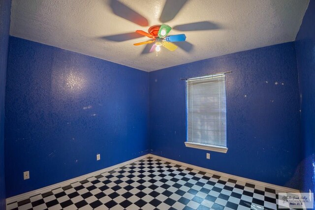 unfurnished room with tile patterned floors, a textured ceiling, baseboards, and a ceiling fan