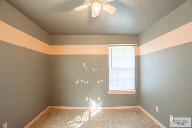 empty room featuring a ceiling fan and baseboards