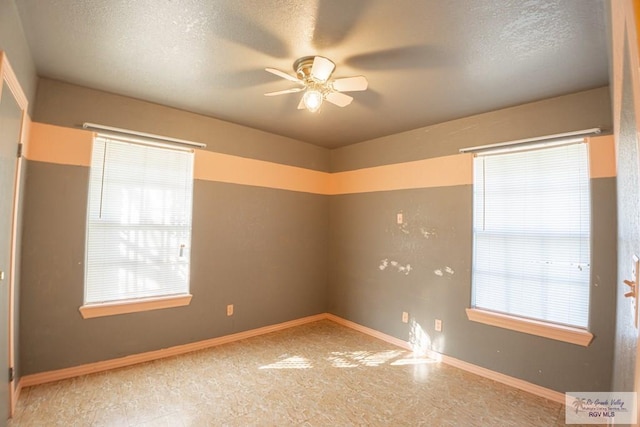 empty room with ceiling fan, baseboards, and a textured ceiling