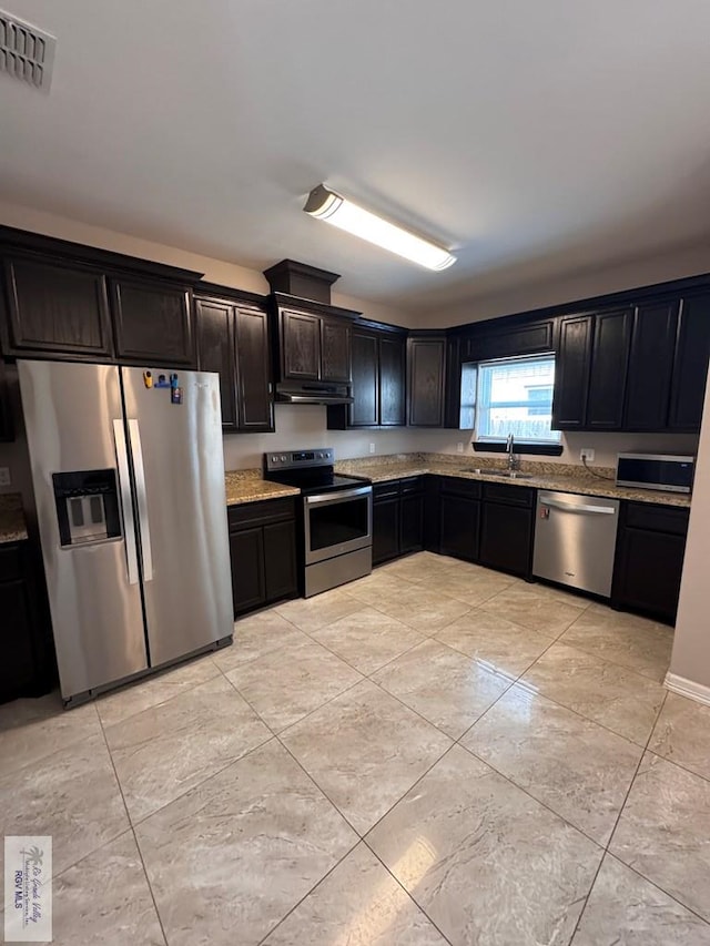 4805 N Westgate Cir, Harlingen, TX 78552 - kitchen featuring appliances with stainless steel finishes, under cabinet range hood, a sink, light stone countertops, and light tile patterned floors
