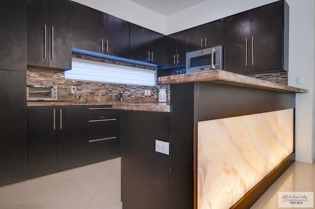 kitchen with decorative backsplash, light tile patterned floors, and stone countertops