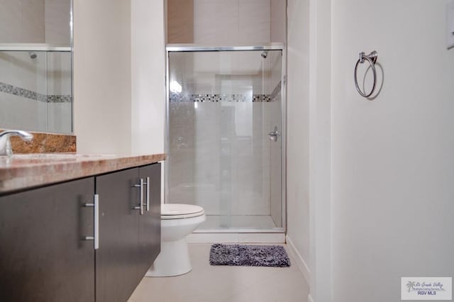 bathroom with toilet, vanity, tile patterned floors, and a shower with door