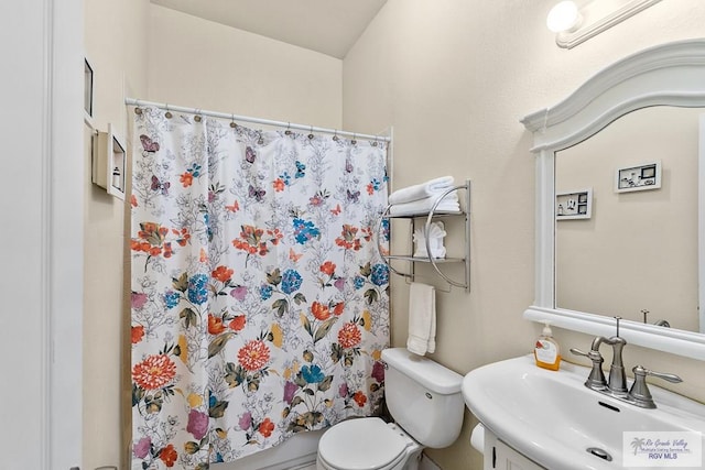 bathroom with a shower with shower curtain, toilet, and sink