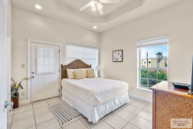 tiled bedroom featuring a tray ceiling, multiple windows, and ceiling fan