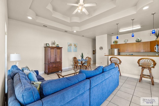 tiled living room featuring a tray ceiling and ceiling fan