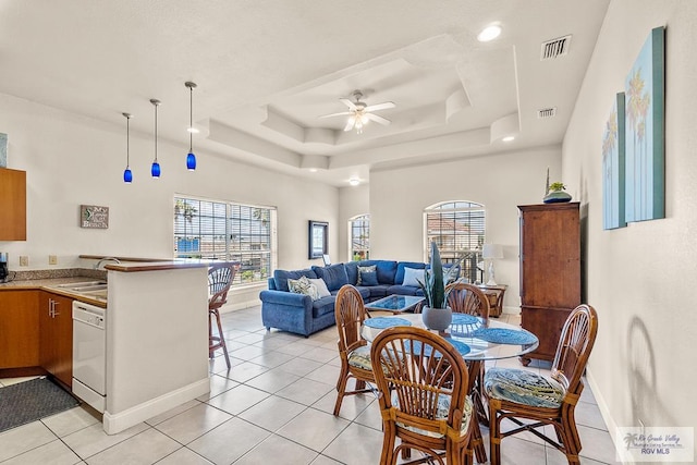 dining room featuring a raised ceiling, ceiling fan, sink, and light tile patterned floors