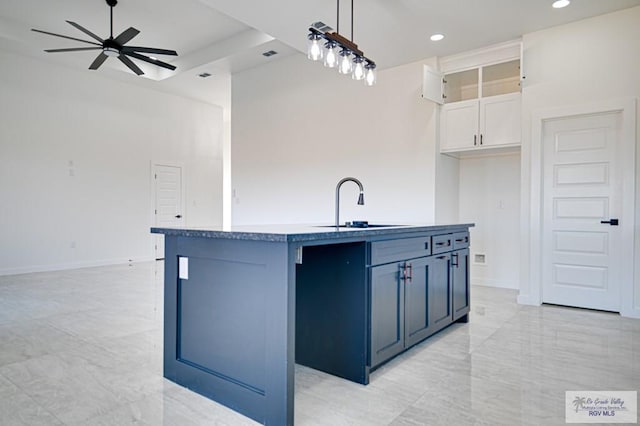 kitchen with pendant lighting, an island with sink, a ceiling fan, a sink, and white cabinetry