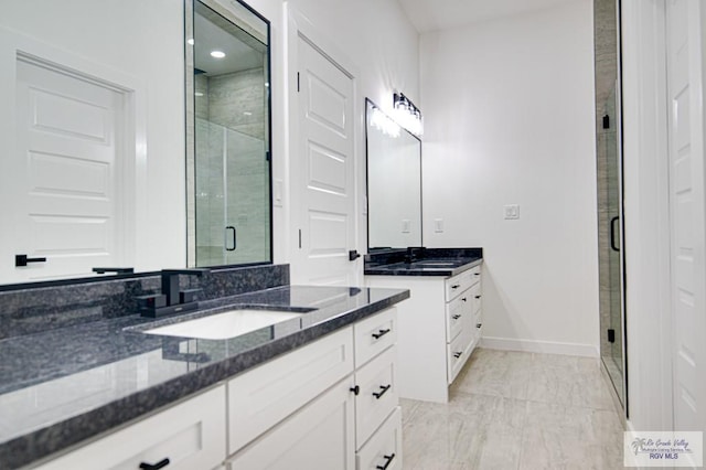 bathroom with baseboards, two vanities, a stall shower, a sink, and marble finish floor