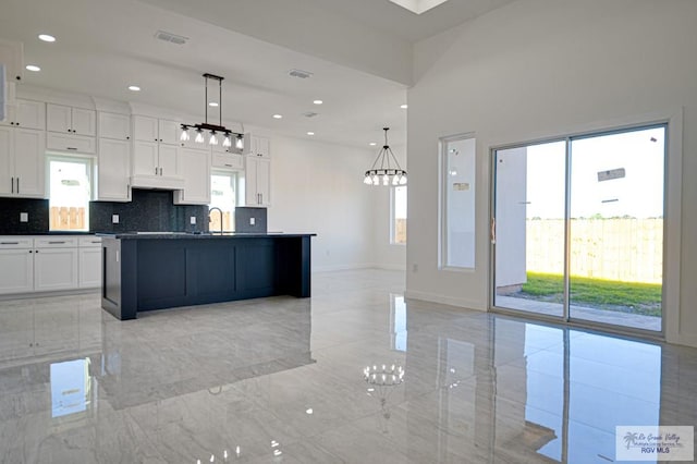 kitchen featuring decorative backsplash, dark countertops, a healthy amount of sunlight, and white cabinetry