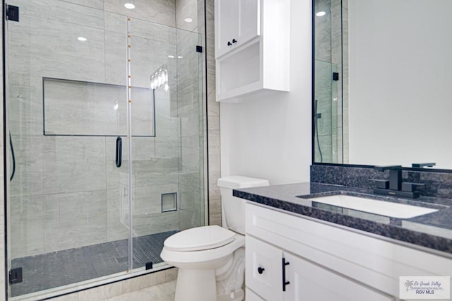 bathroom with vanity, a shower stall, and toilet