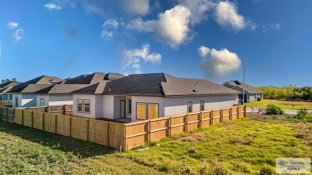 rear view of house featuring stucco siding and fence