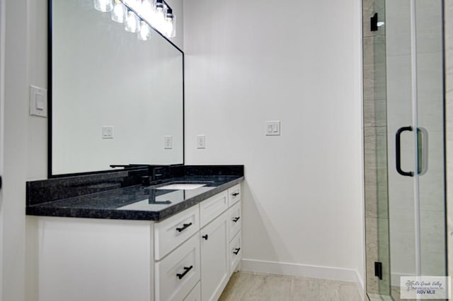 full bath with vanity, a shower stall, and baseboards