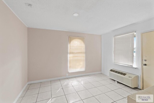 unfurnished room featuring light tile patterned floors, a textured ceiling, and a wall mounted AC