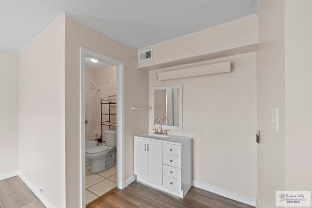 full bathroom with vanity, hardwood / wood-style flooring, toilet, and tiled shower / bath