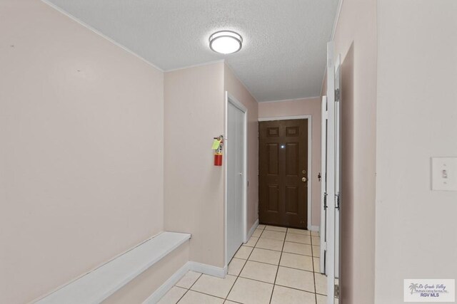 corridor featuring light tile patterned floors and a textured ceiling