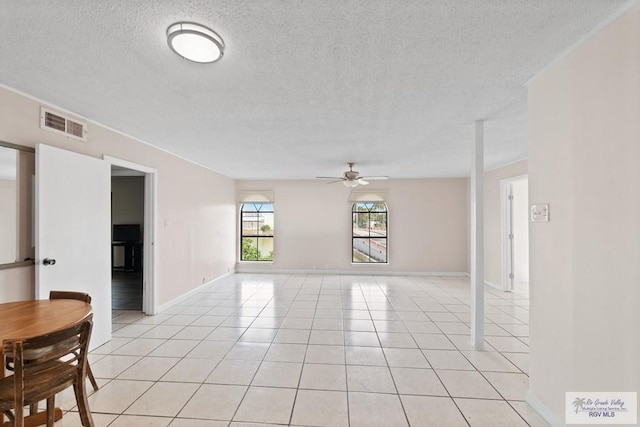 tiled empty room with ceiling fan and a textured ceiling