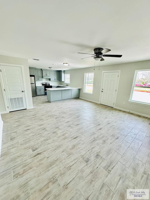 unfurnished living room with ceiling fan, sink, and light wood-type flooring