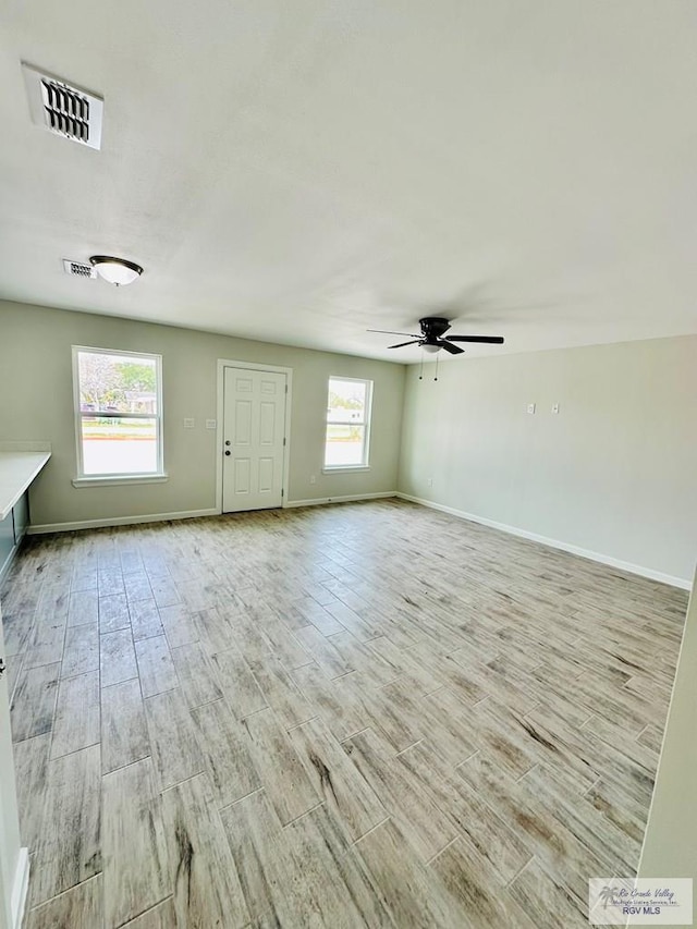 spare room featuring ceiling fan, light hardwood / wood-style floors, and a wealth of natural light