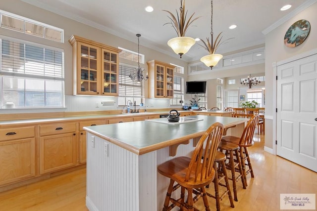 kitchen featuring a center island, crown molding, cooktop, a breakfast bar area, and a sink