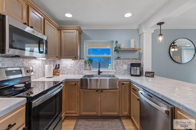 kitchen featuring light wood-style flooring, ornamental molding, a sink, appliances with stainless steel finishes, and backsplash