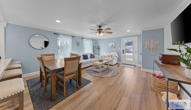 dining room featuring crown molding, light wood-style flooring, a ceiling fan, and baseboards