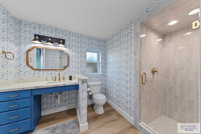 full bath with toilet, wood finished floors, a shower stall, and wallpapered walls