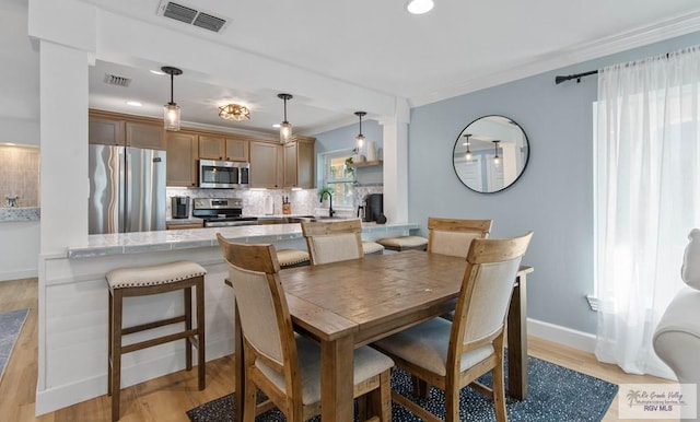 dining room with visible vents, light wood-style flooring, and crown molding