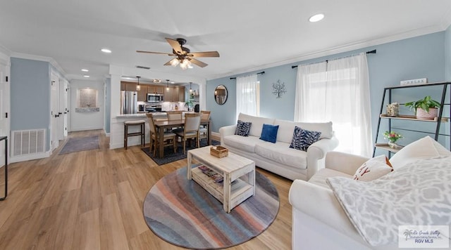 living area featuring crown molding, recessed lighting, visible vents, and light wood-type flooring