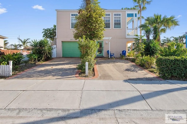 view of front of house featuring stucco siding, concrete driveway, an attached garage, and fence